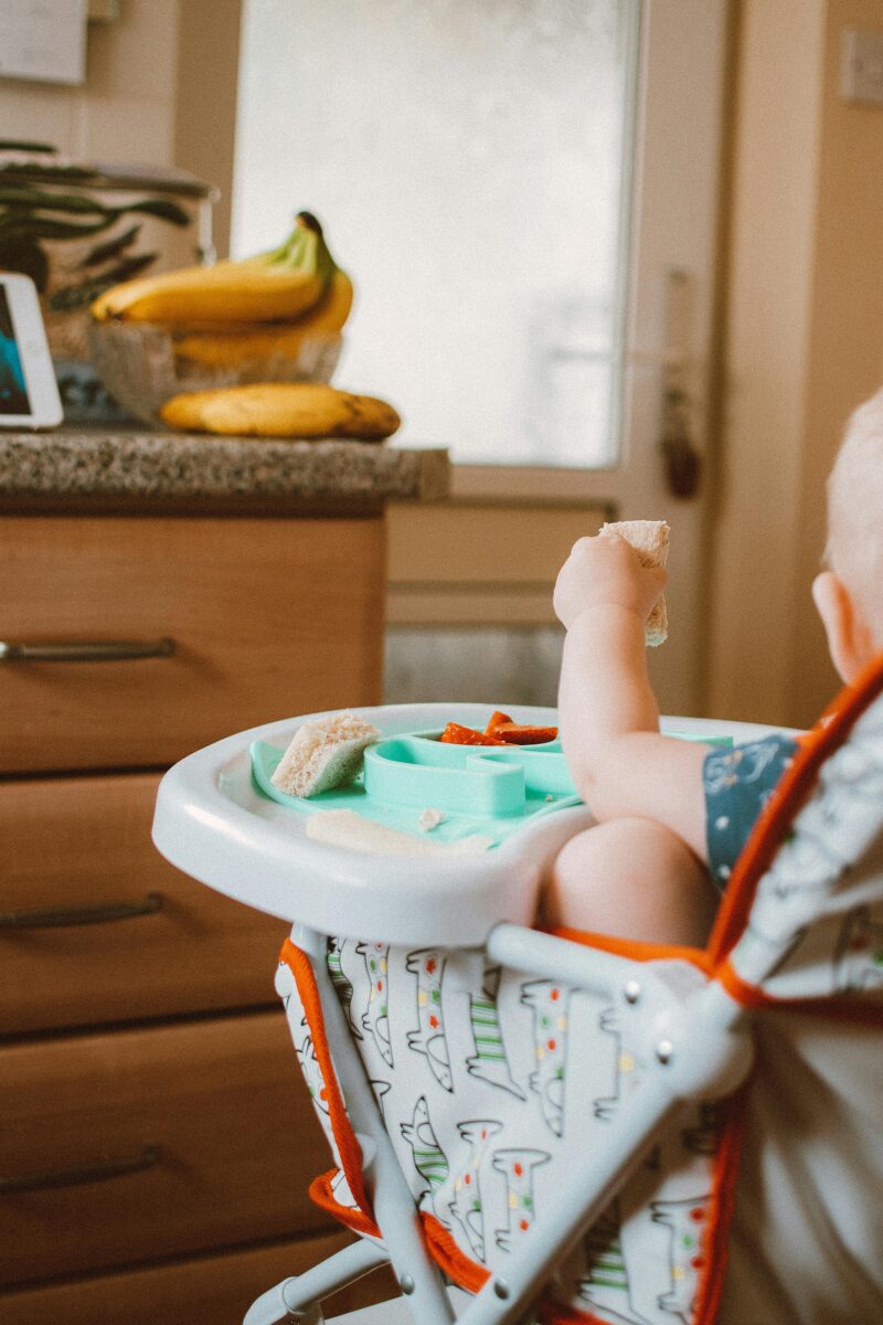 Baby von hinten im Hochstuhl beim ersten Essen – Beikost-Start